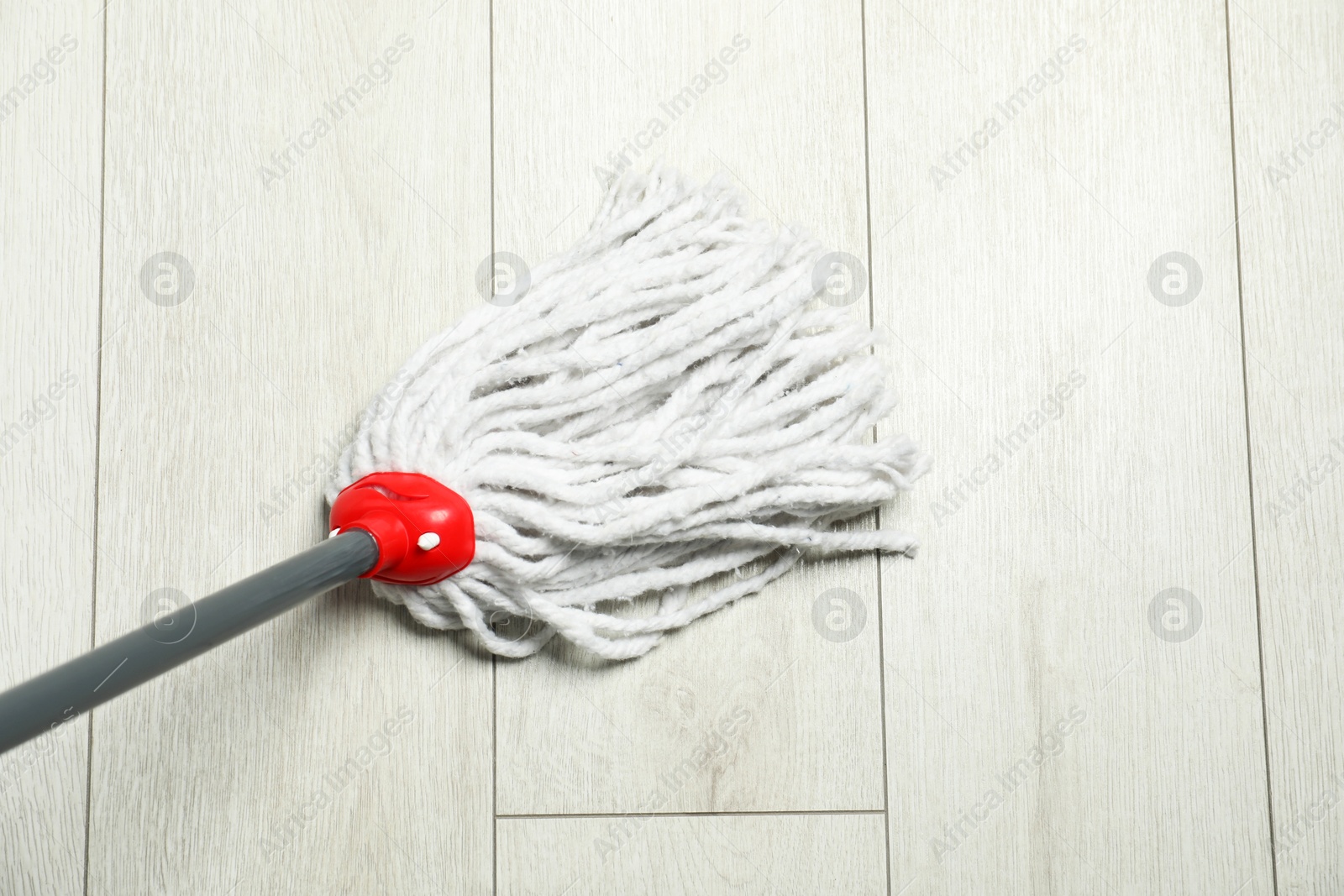 Photo of String mop on wooden floor, above view. Cleaning equipment