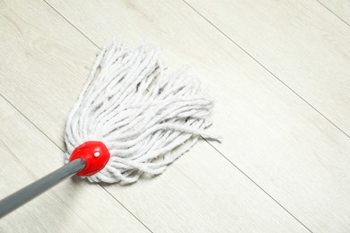 String mop on wooden floor, above view. Space for text