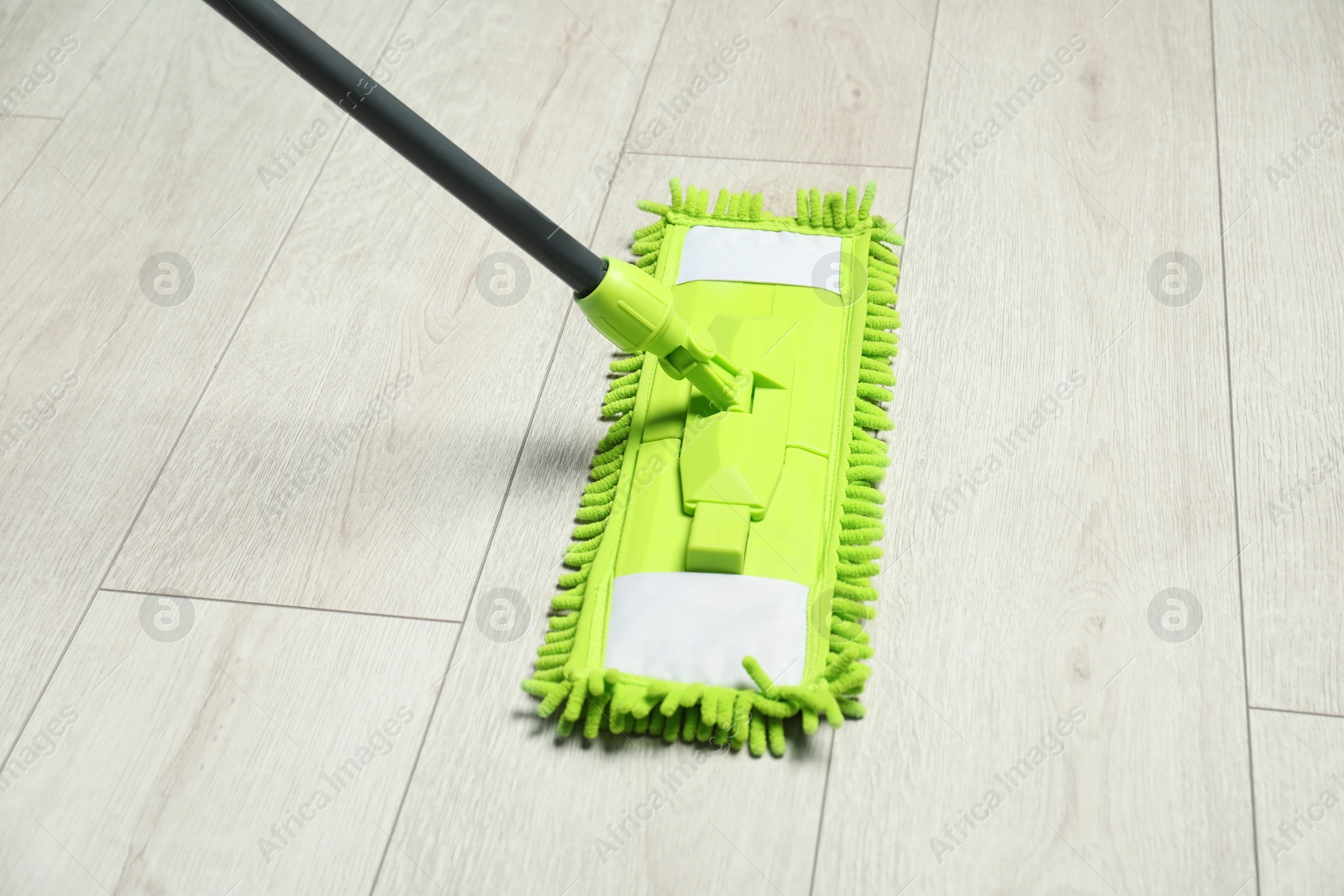 Photo of Microfiber mop on wooden floor. Cleaning equipment