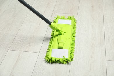 Photo of Microfiber mop on wooden floor. Cleaning equipment