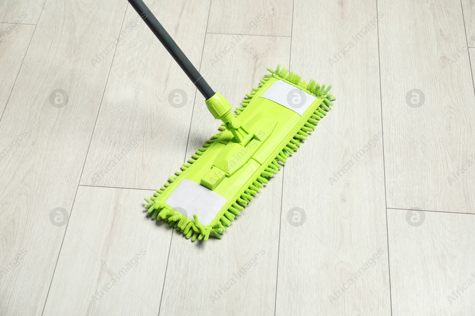 Photo of Microfiber mop on wooden floor. Cleaning equipment