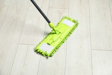 Photo of Microfiber mop on wooden floor. Cleaning equipment