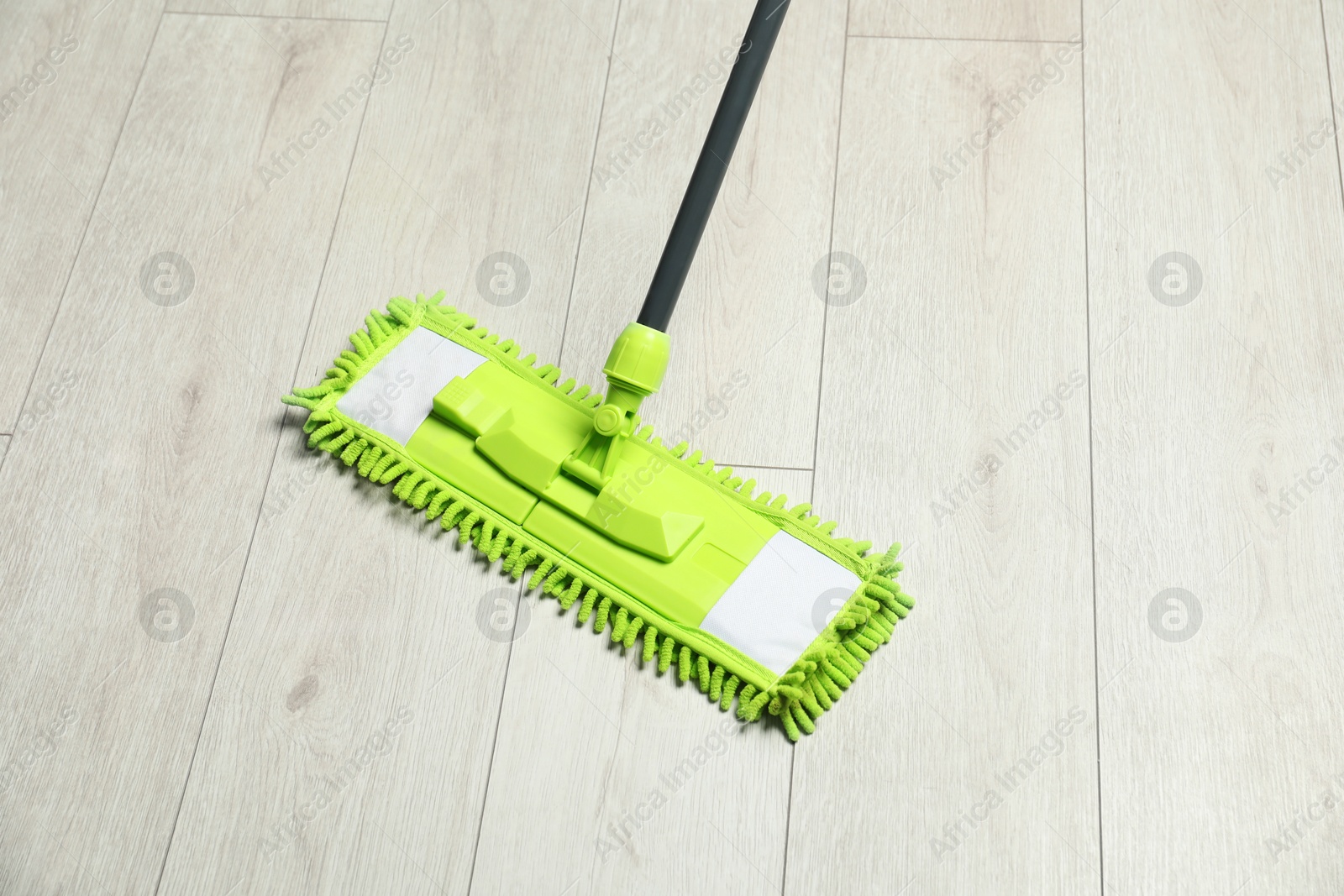 Photo of Microfiber mop on wooden floor. Cleaning equipment