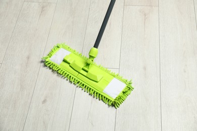 Photo of Microfiber mop on wooden floor. Cleaning equipment