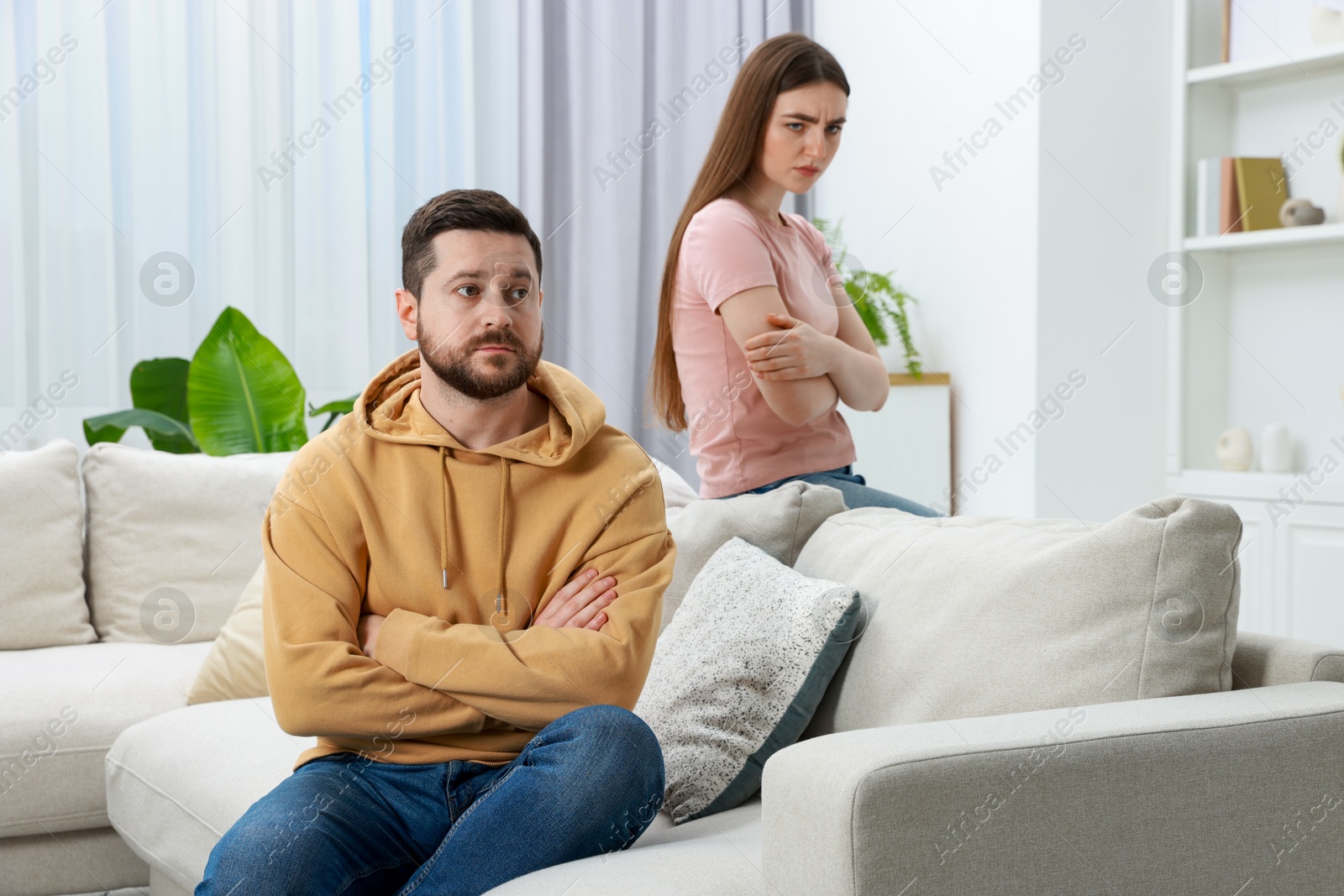 Photo of Resentful couple with crossed arms sitting on couch at home