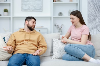 Photo of Woman sitting on couch near her resentful boyfriend at home