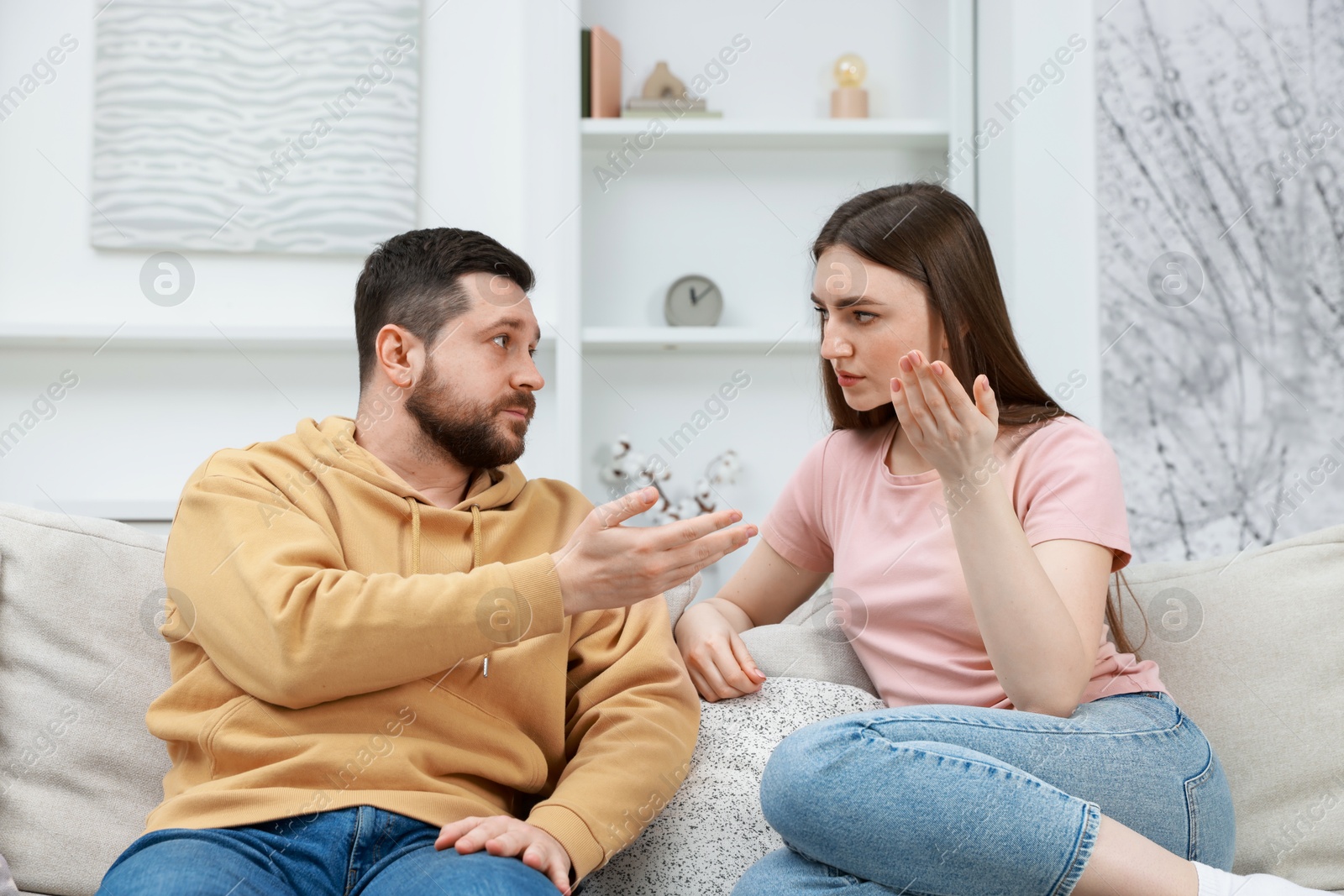 Photo of Angry couple arguing on couch at home