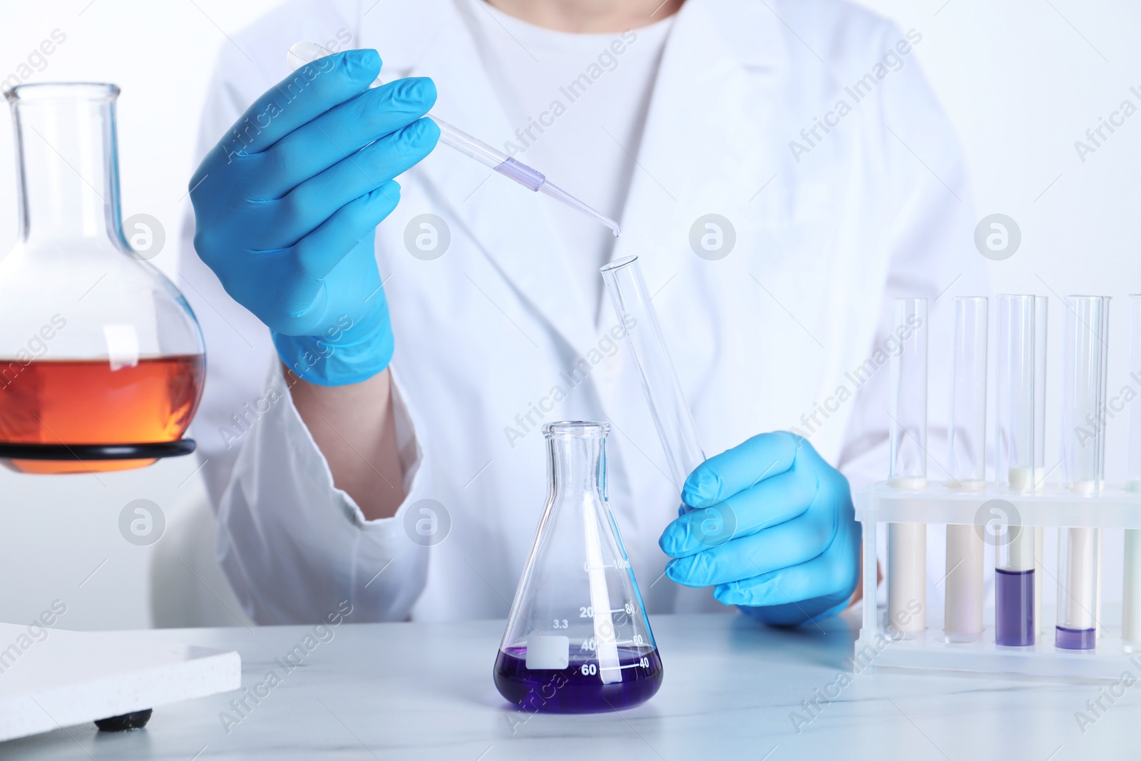 Photo of Laboratory testing. Scientist working with glassware at white marble table, closeup