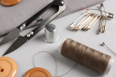 Photo of Different sewing supplies on light grey background, closeup