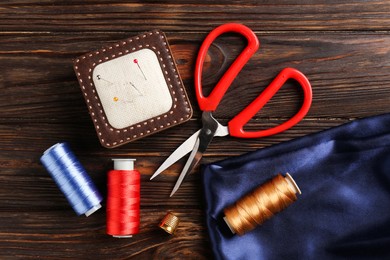 Photo of Different sewing supplies on wooden table, flat lay