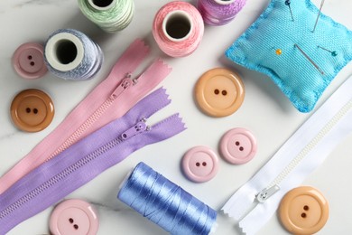 Photo of Different sewing supplies on white marble table, flat lay