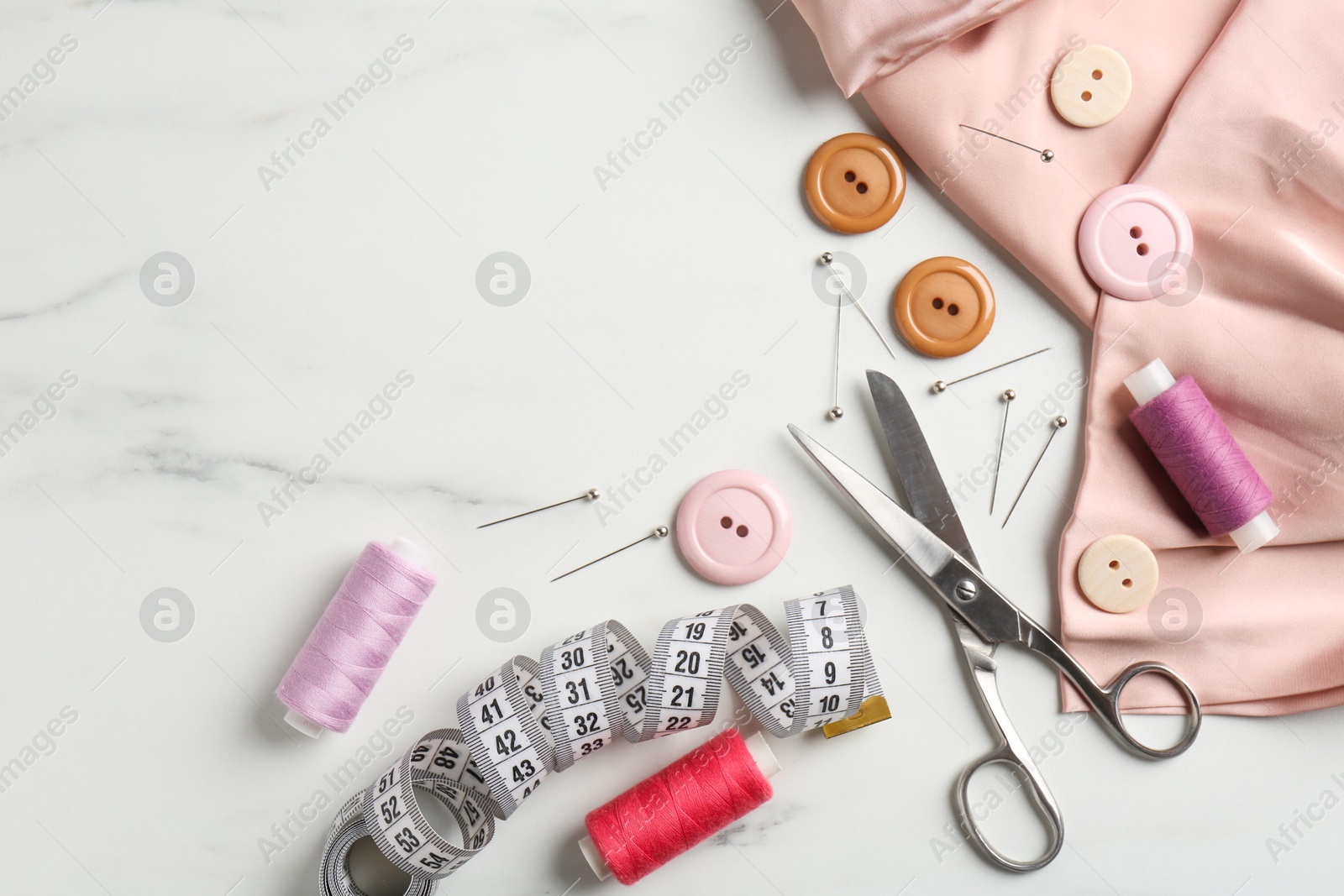 Photo of Different sewing supplies on white marble table, flat lay. Space for text