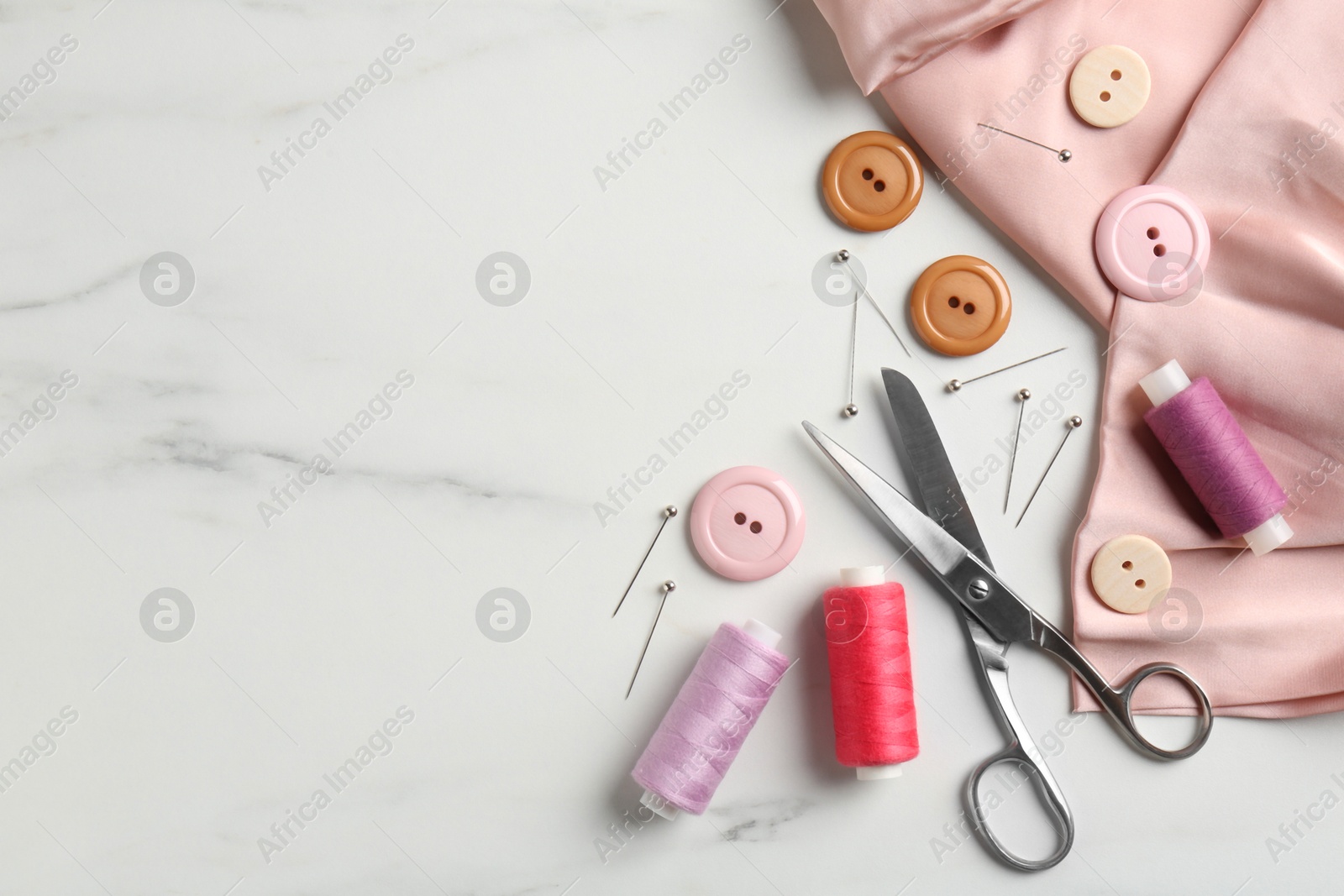 Photo of Different sewing supplies on white marble table, flat lay. Space for text