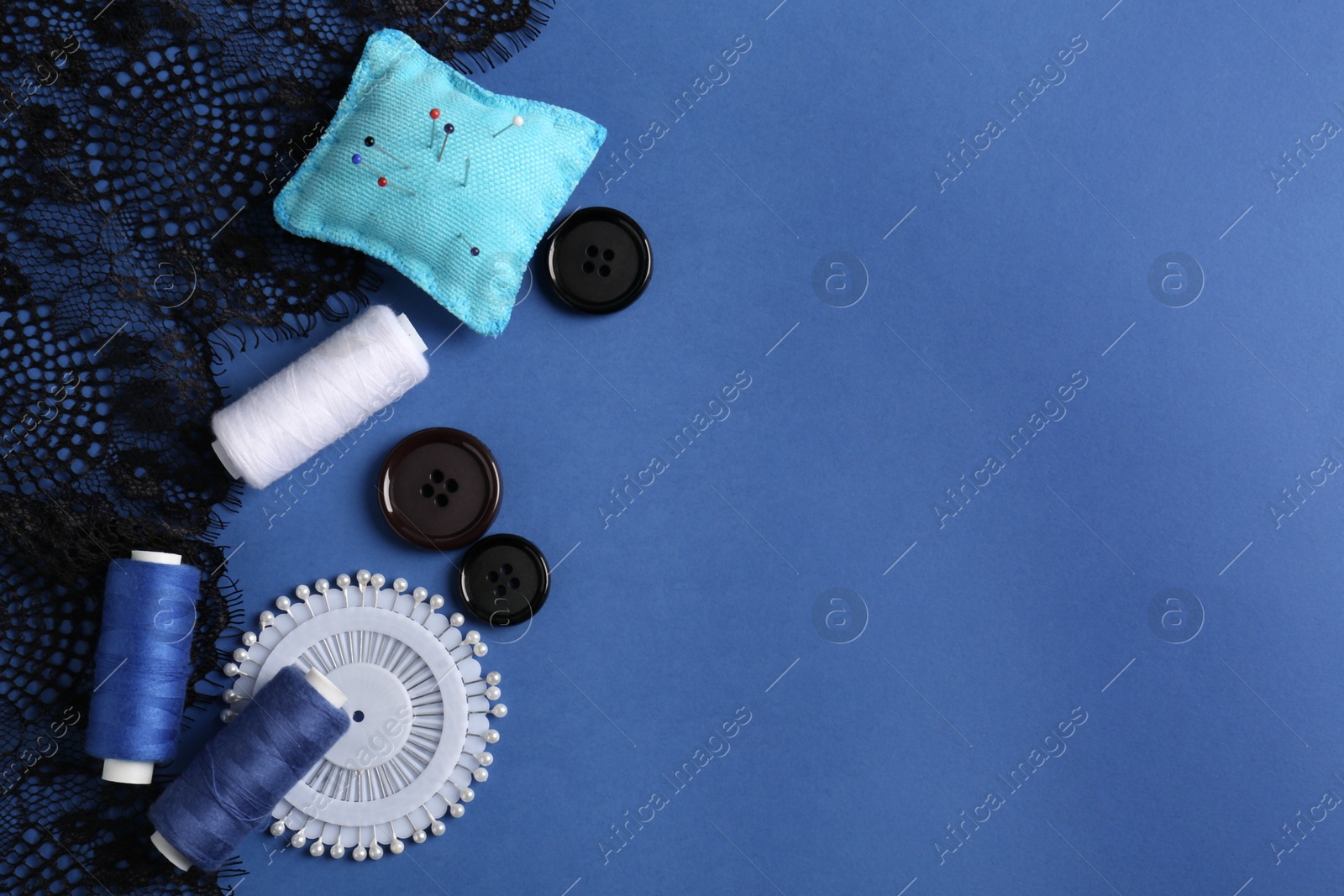 Photo of Different sewing supplies on blue background, flat lay. Space for text