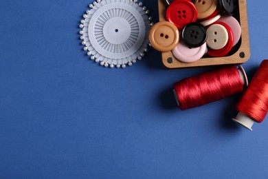 Photo of Different sewing supplies on blue background, flat lay. Space for text