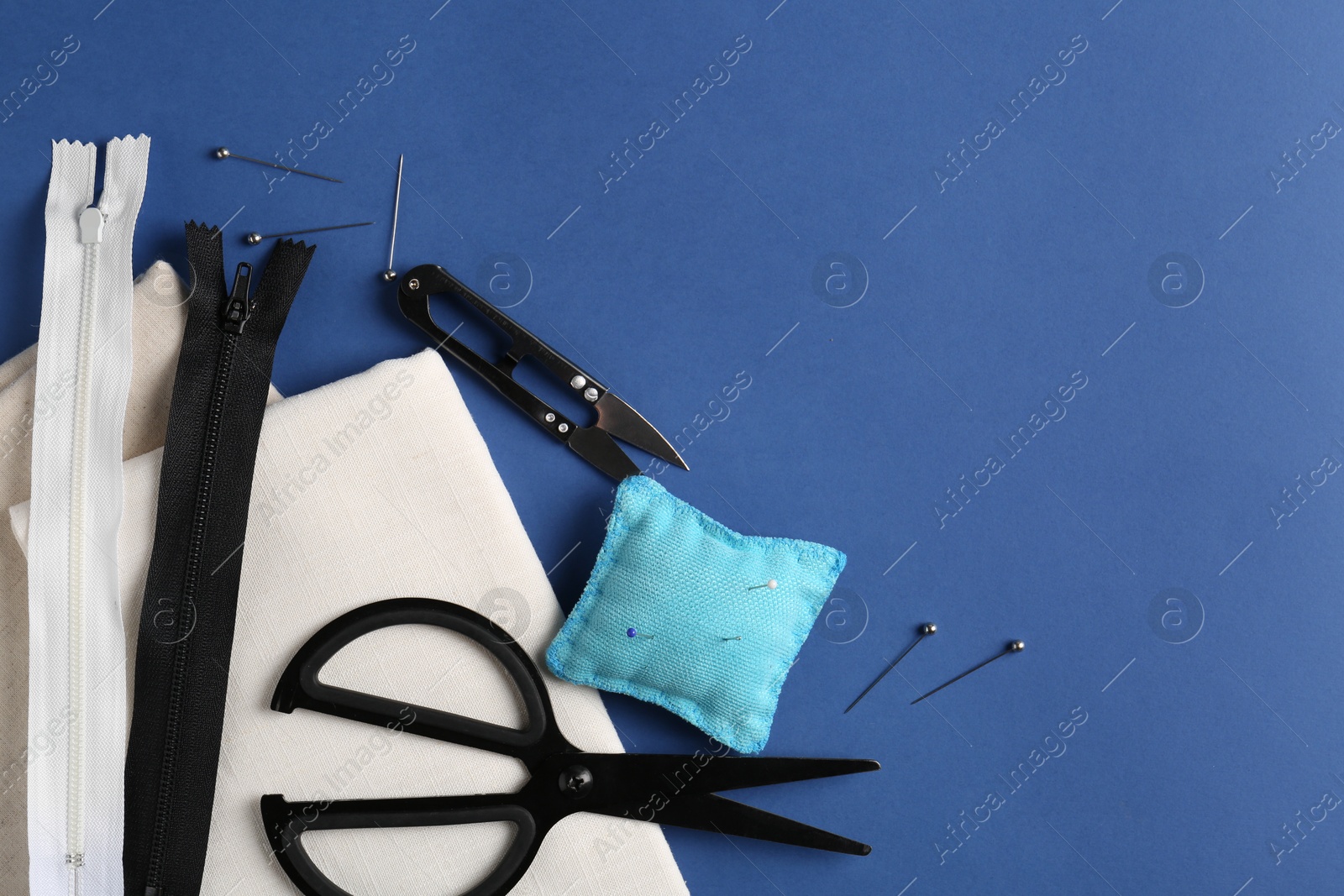 Photo of Different sewing supplies on blue background, flat lay. Space for text