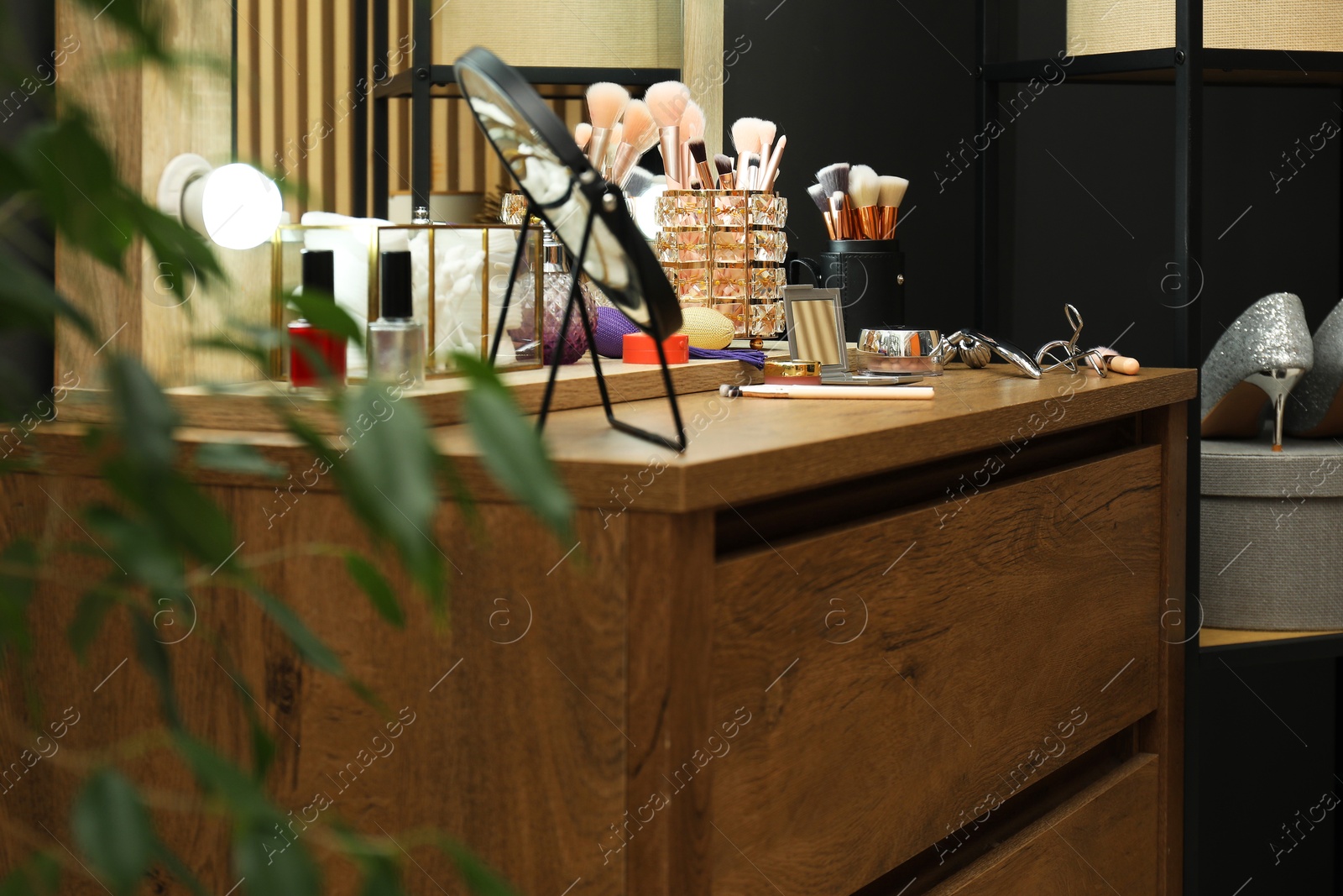 Photo of Makeup room. Mirror and cosmetic products on wooden dresser indoors