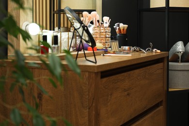 Photo of Makeup room. Mirror and cosmetic products on wooden dresser indoors