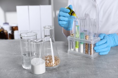 Photo of Laboratory testing. Scientist dripping liquid into test tube at table indoors, closeup