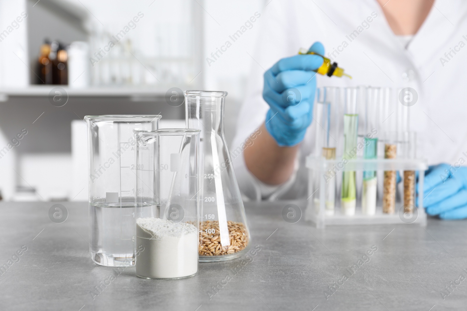 Photo of Laboratory testing. Scientist dripping liquid into test tube at table indoors, focus on glassware with sample