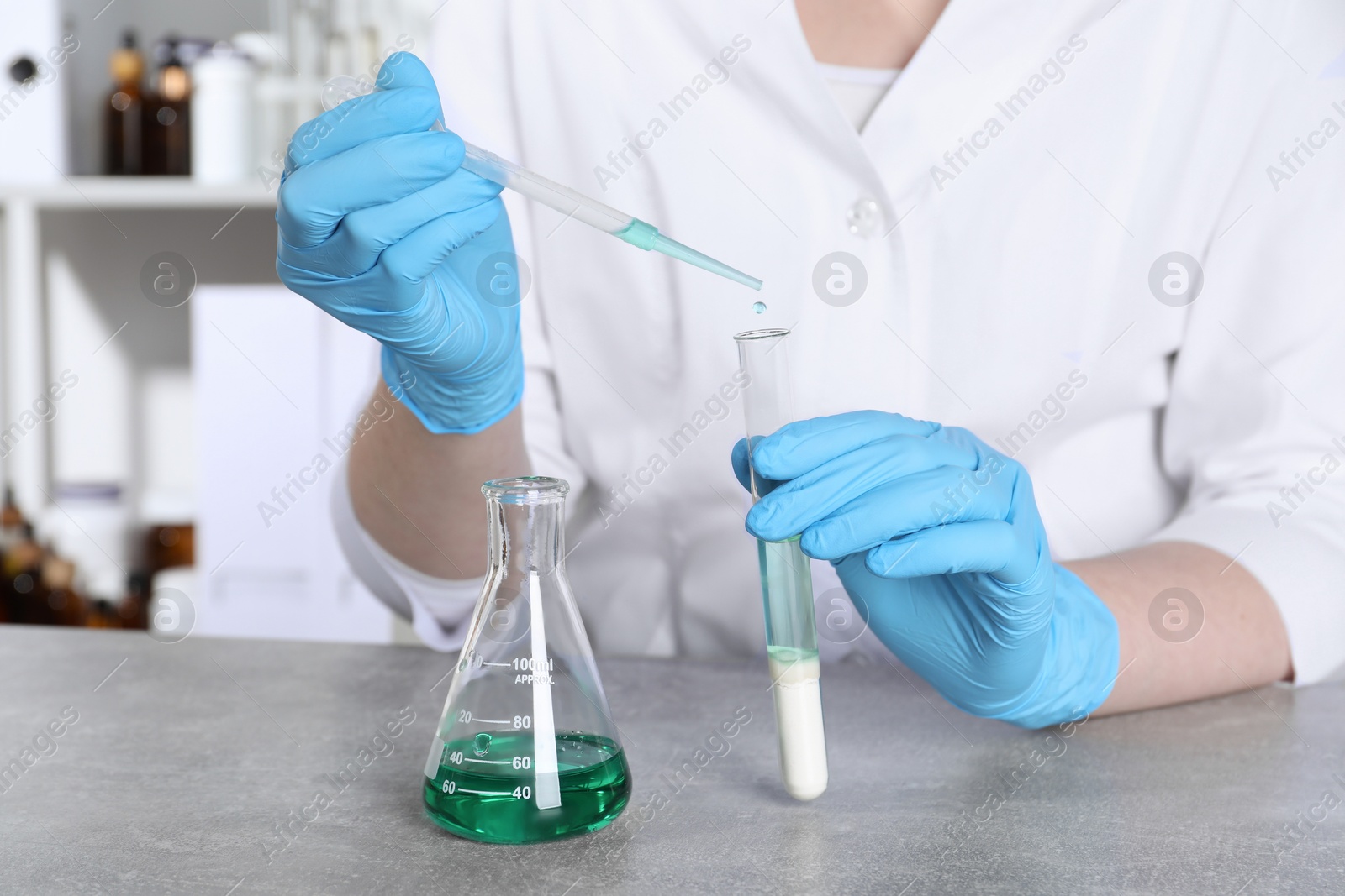 Photo of Laboratory testing. Scientist dripping sample from pipette into test tube at table indoors, closeup