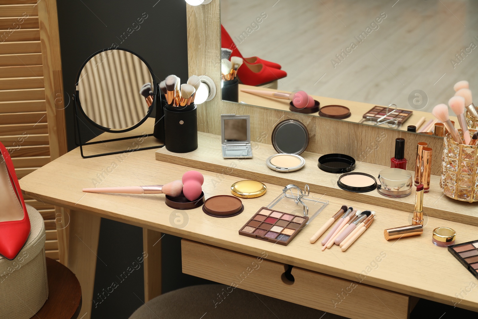 Photo of Makeup room. Mirrors and cosmetic products on wooden dressing table indoors