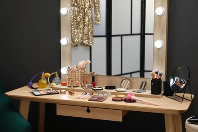 Photo of Makeup room. Wooden dressing table with mirror and different beauty products indoors