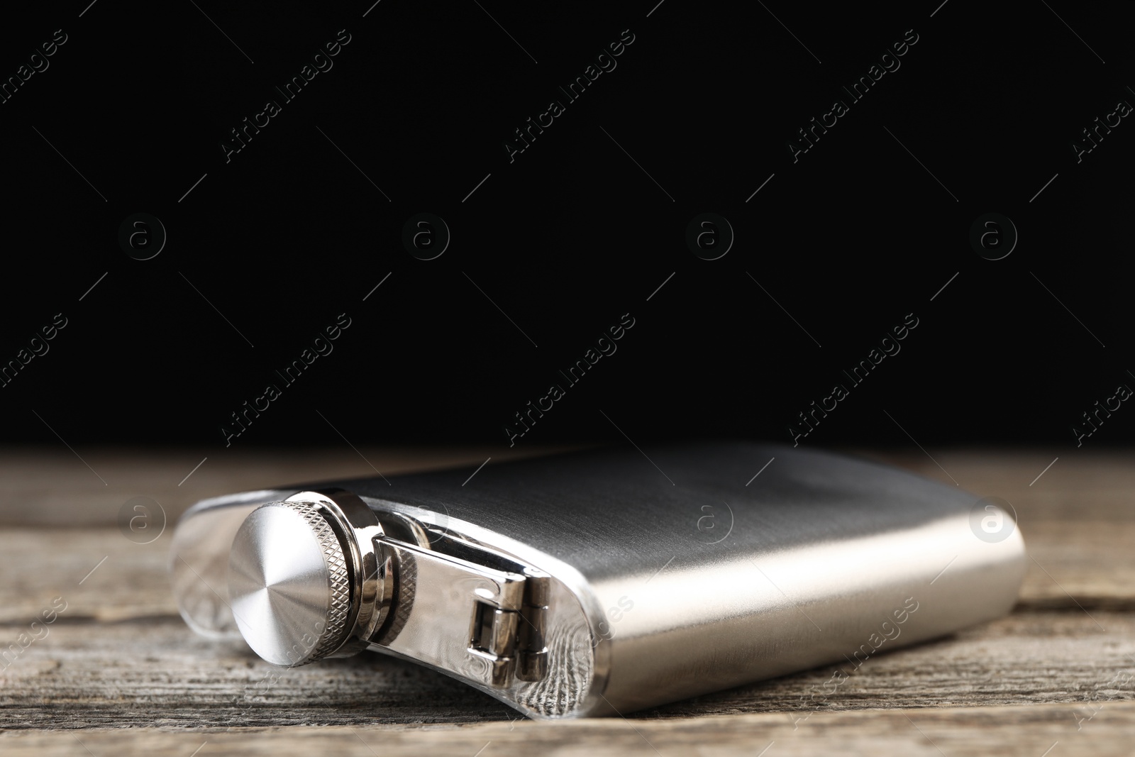 Photo of One hip flask on wooden table, closeup