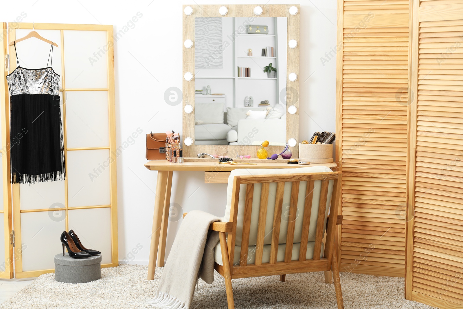 Photo of Makeup room. Mirror, wooden dressing table, different beauty products, shoes and armchair indoors