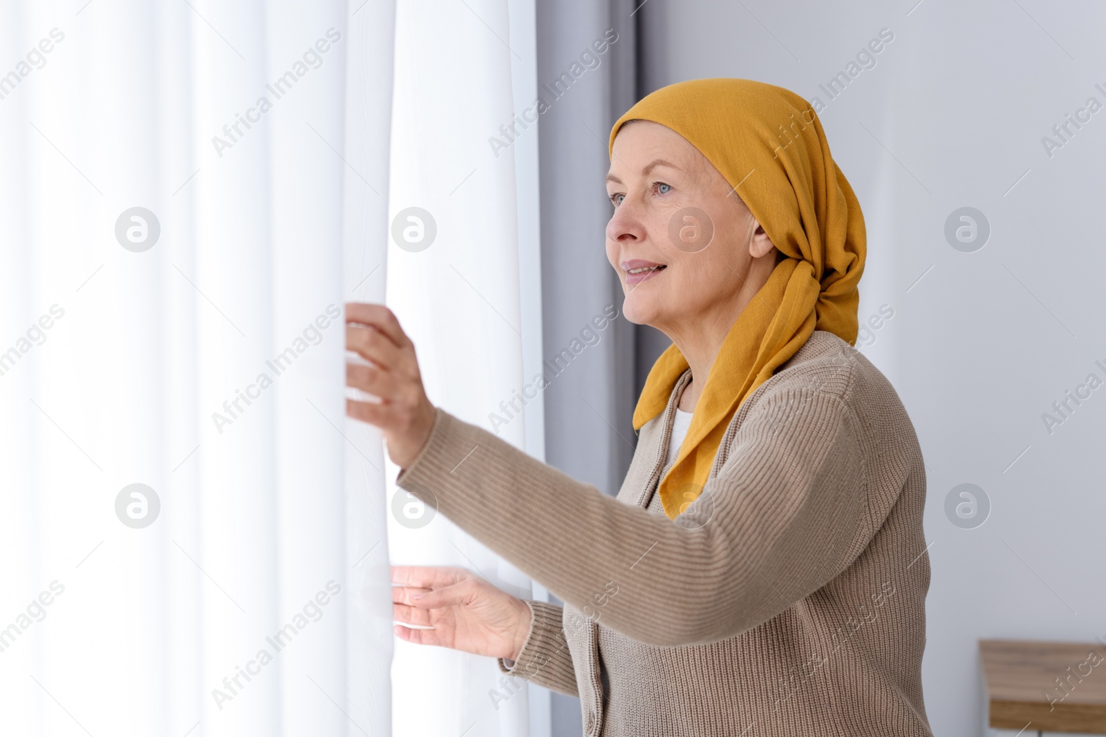 Photo of Senior woman with cancer near window at home