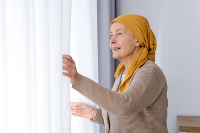 Photo of Senior woman with cancer near window at home