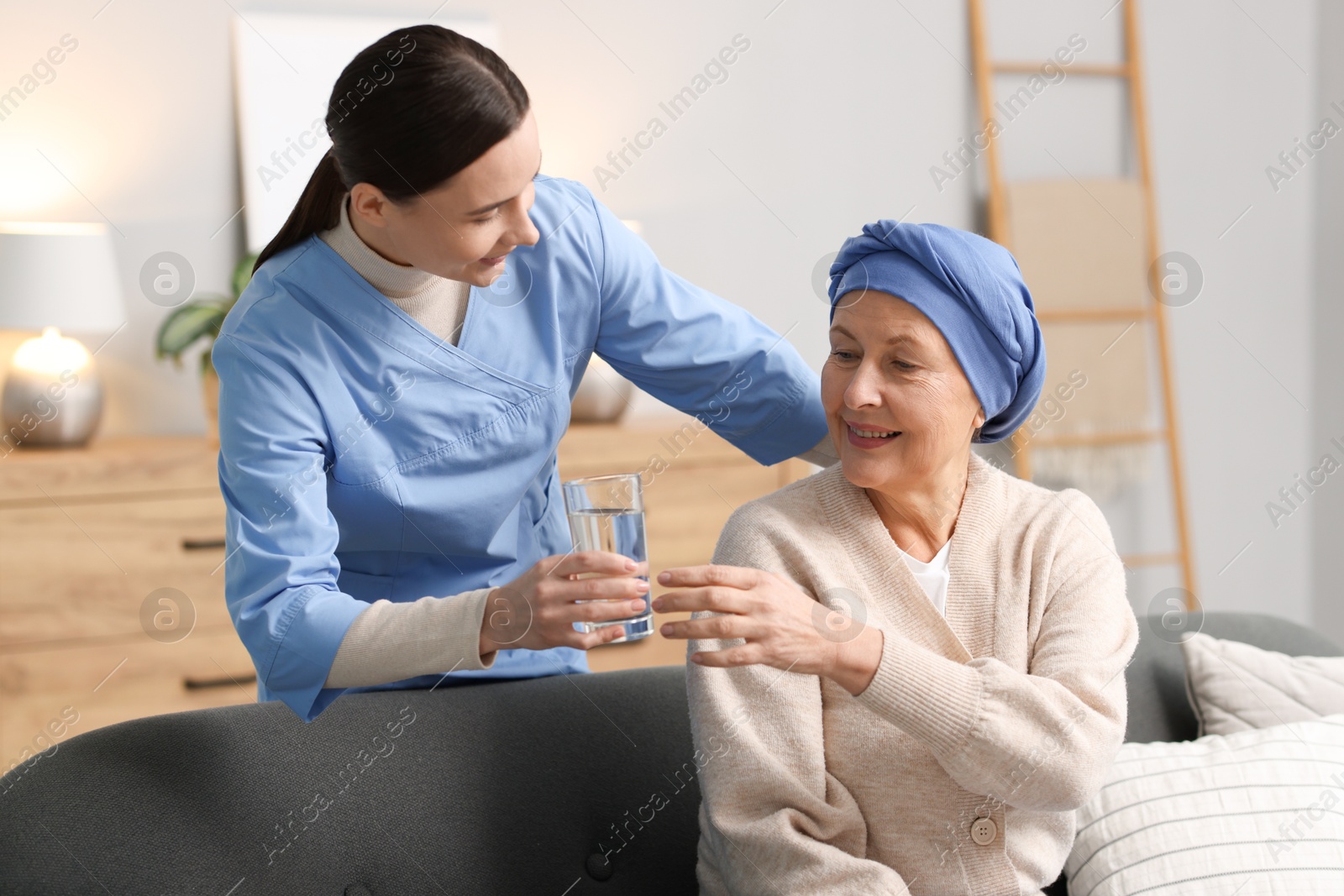 Photo of Nurse giving water to woman with cancer at home