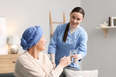 Photo of Nurse giving water to woman with cancer at home