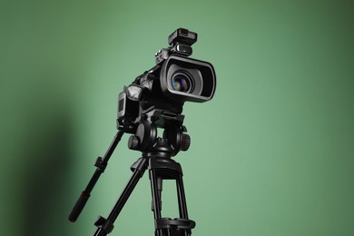 Photo of Modern professional video camera on greyish green background