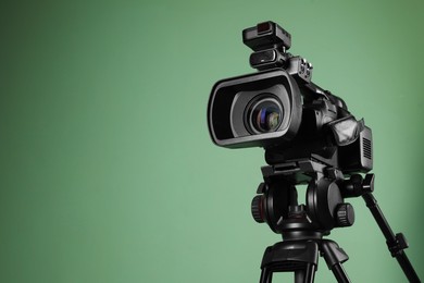 Photo of Modern professional video camera on greyish green background, space for text