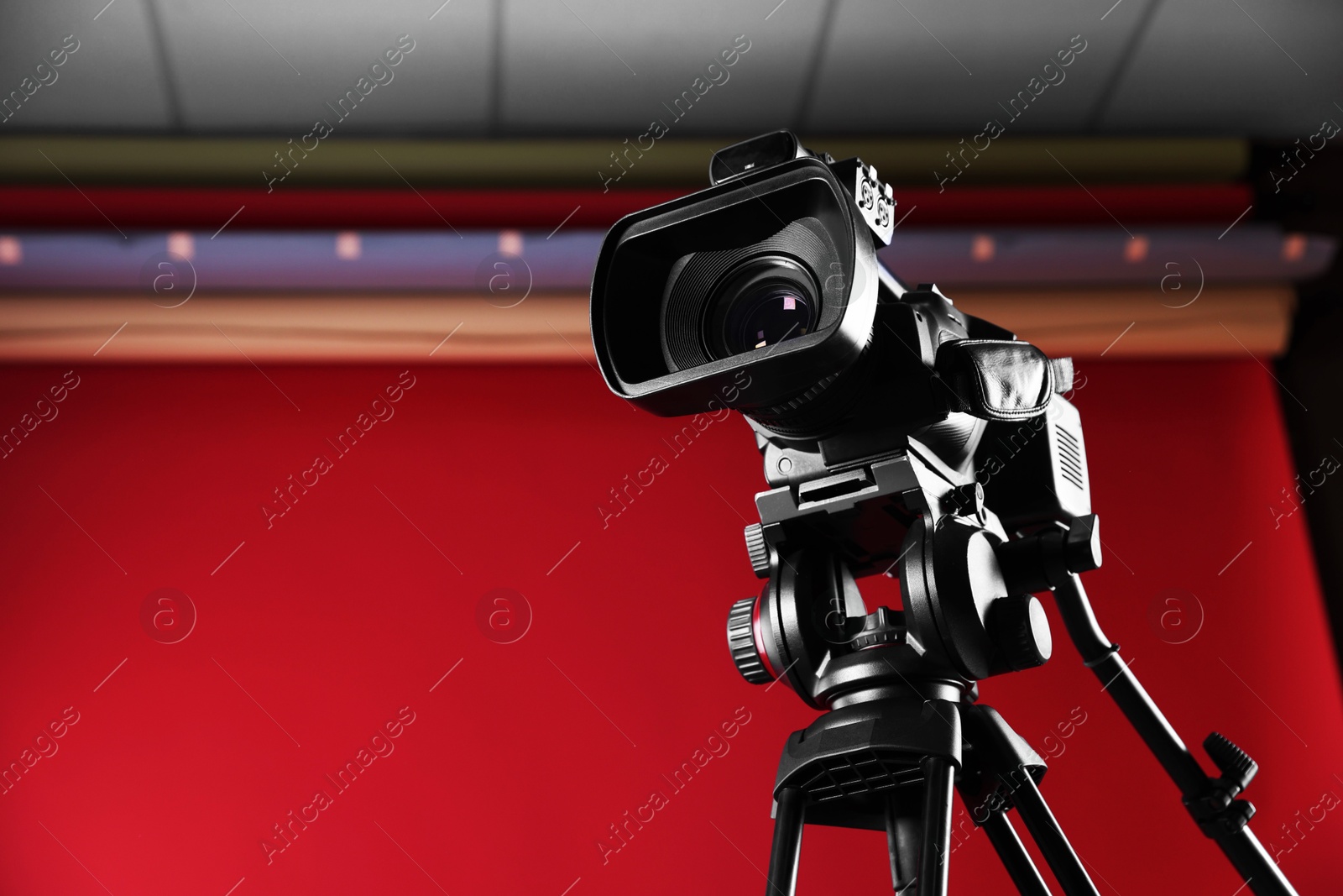 Photo of Modern video camera with tripod in stylish studio, space for text