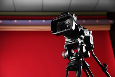 Photo of Modern video camera with tripod in stylish studio, space for text