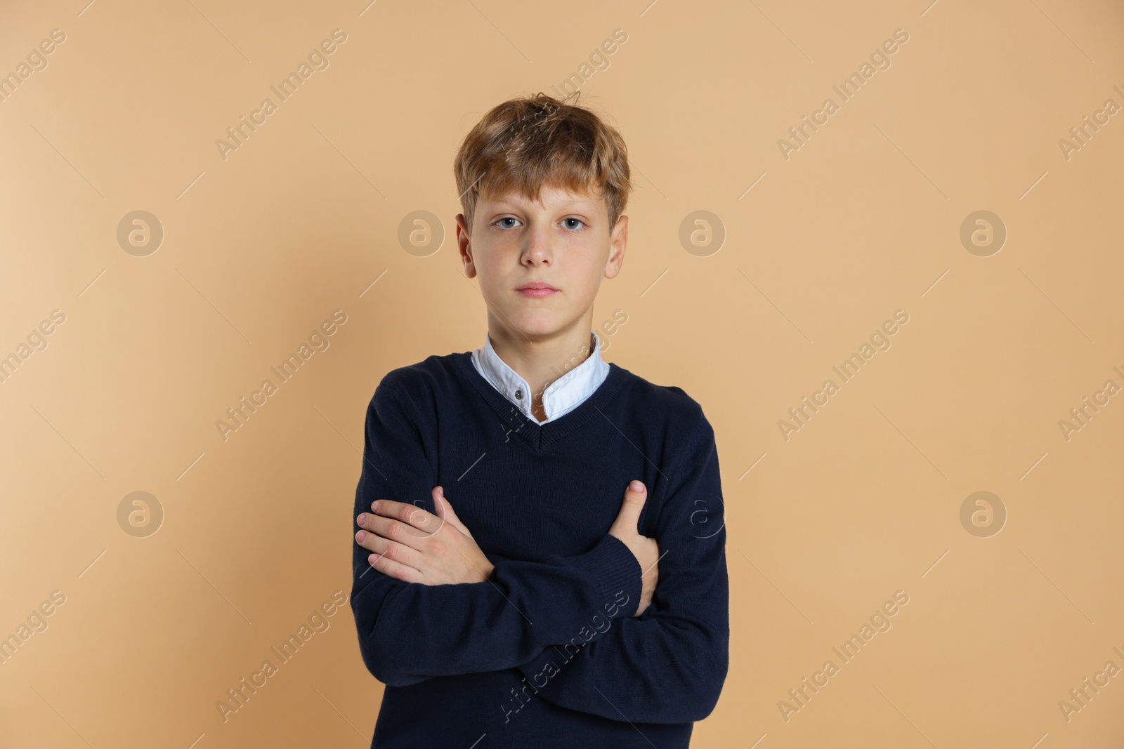 Photo of Portrait of teenage boy with crossed arms on beige background