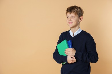 Photo of Portrait of teenage boy with books on beige background, space for text