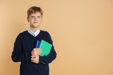 Photo of Portrait of teenage boy with books on beige background, space for text