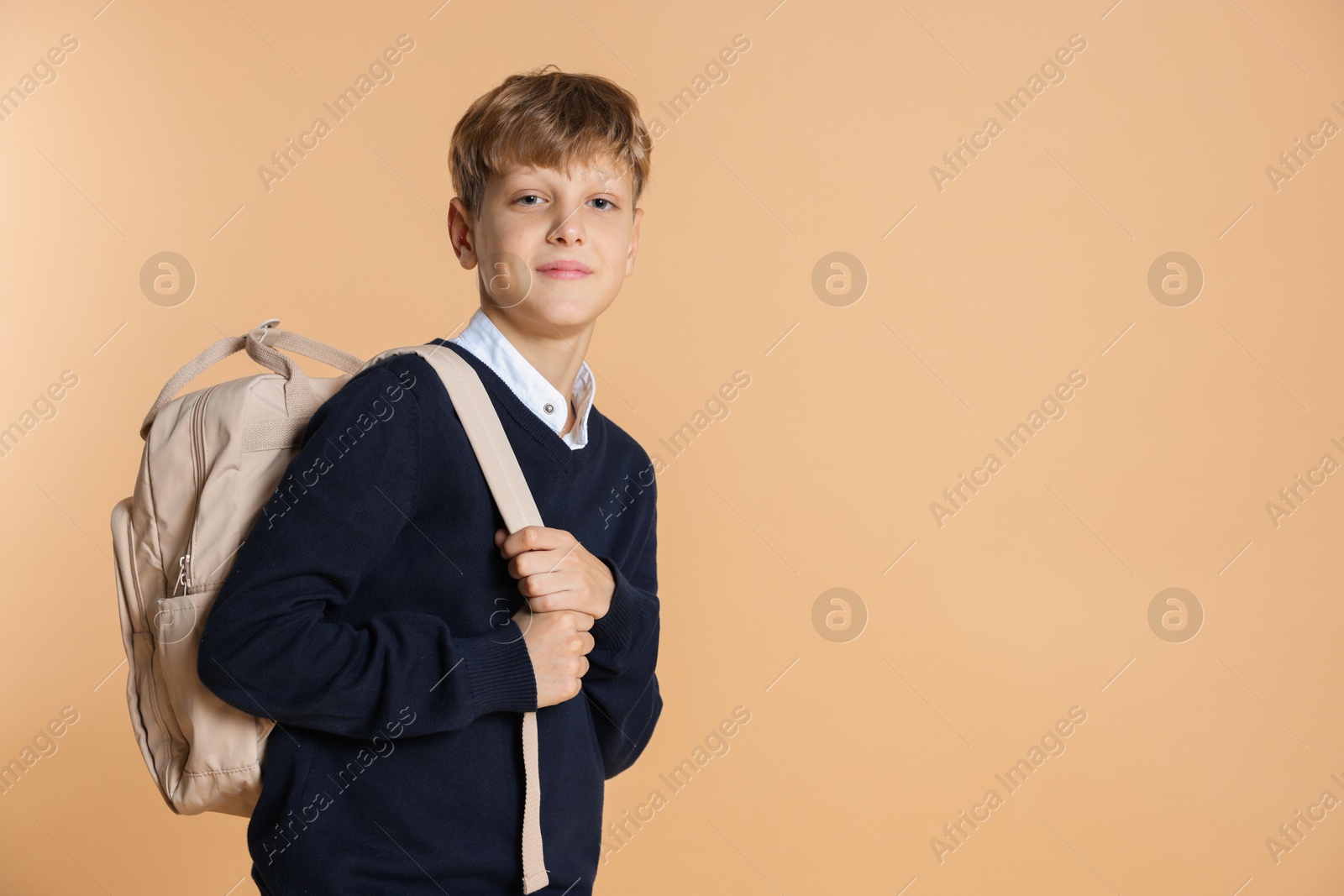 Photo of Portrait of teenage boy with backpack on beige background, space for text