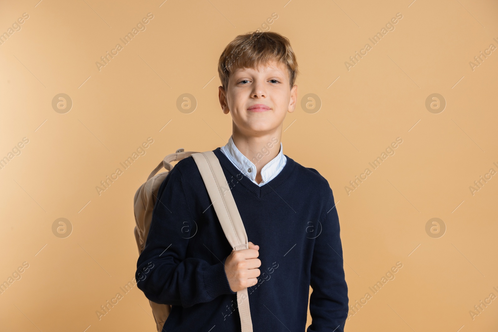 Photo of Portrait of teenage boy with backpack on beige background