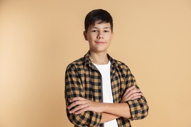 Photo of Portrait of teenage boy with crossed arms on beige background