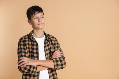 Photo of Portrait of teenage boy with crossed arms on beige background, space for text