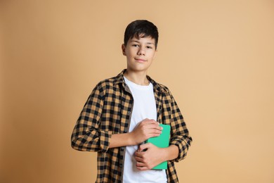 Photo of Portrait of teenage boy with books on beige background