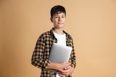 Photo of Portrait of teenage boy with laptop on beige background