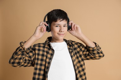 Photo of Portrait of teenage boy in headphones on beige background