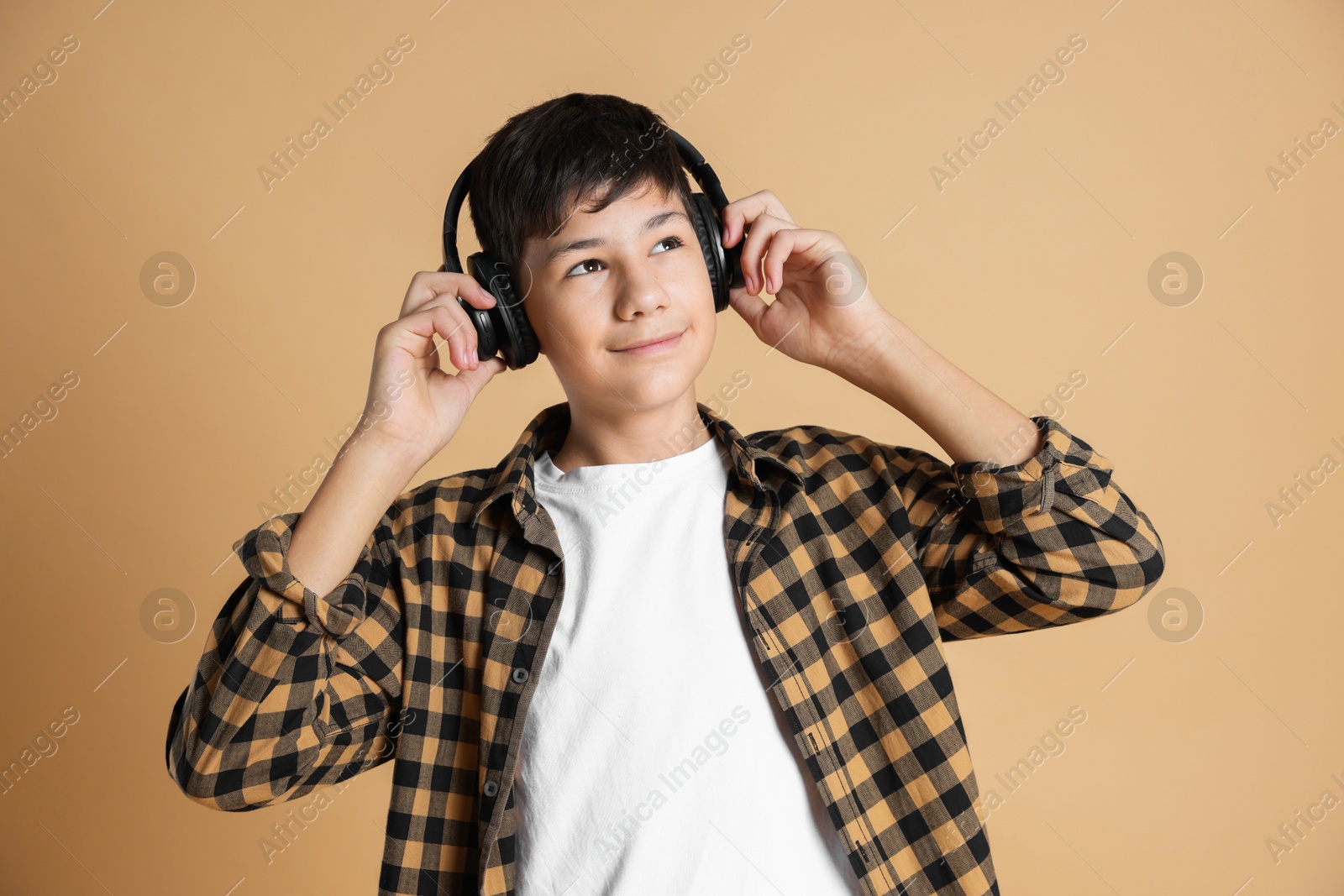 Photo of Portrait of teenage boy in headphones on beige background