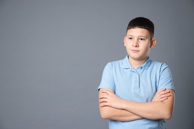 Photo of Portrait of teenage boy with crossed arms on grey background, space for text