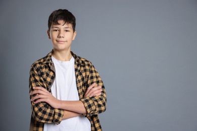 Photo of Portrait of teenage boy with crossed arms on grey background, space for text